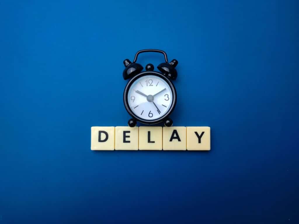 Diboll Fitness Opening Delayed - Black clock on Blue Background with "Delay" underneath in Scrabble Tiles