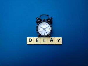 Diboll Fitness Opening Delayed - Black clock on Blue Background with "Delay" underneath in Scrabble Tiles