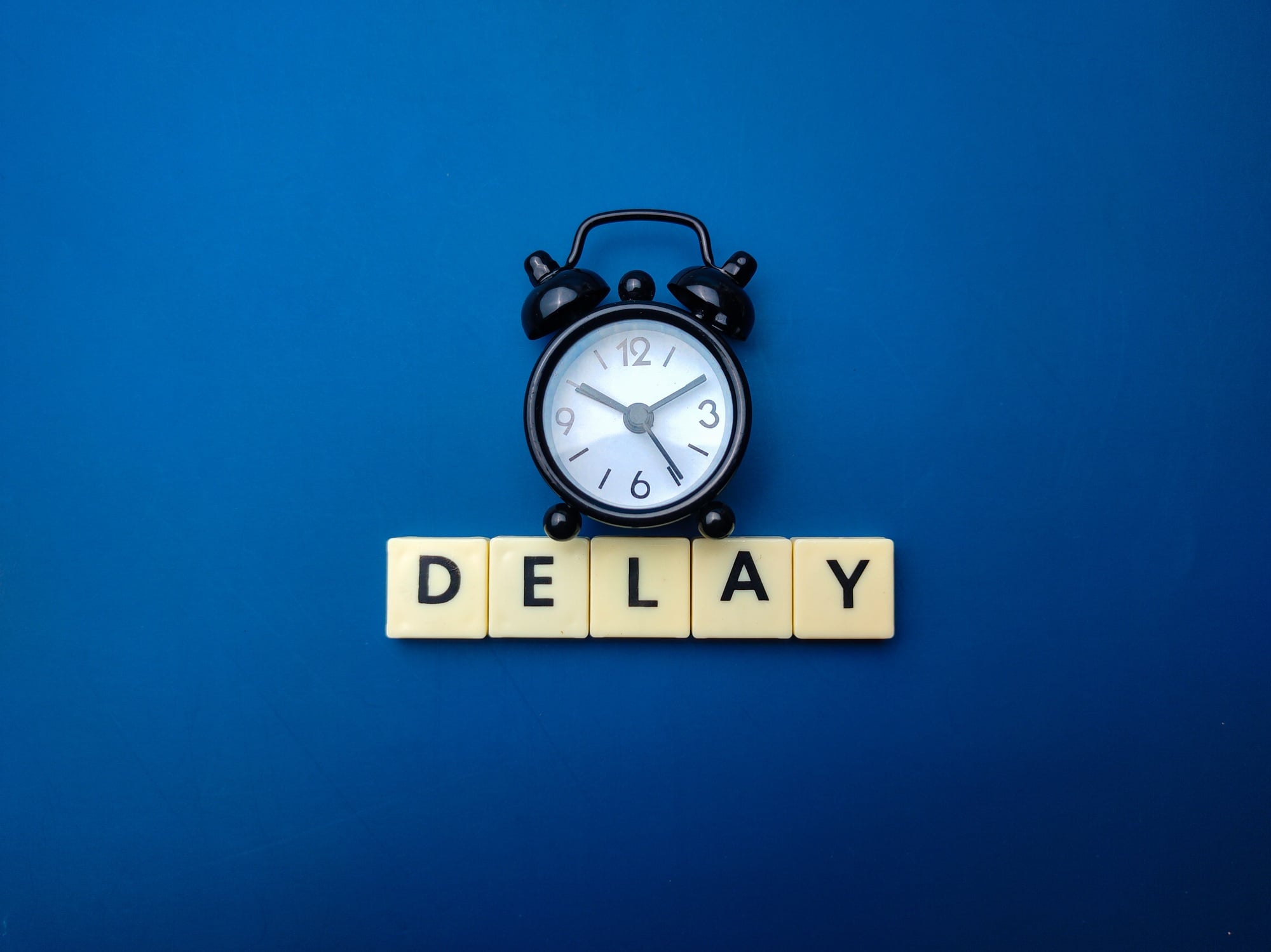 Diboll Fitness Opening Delayed - Black clock on Blue Background with "Delay" underneath in Scrabble Tiles